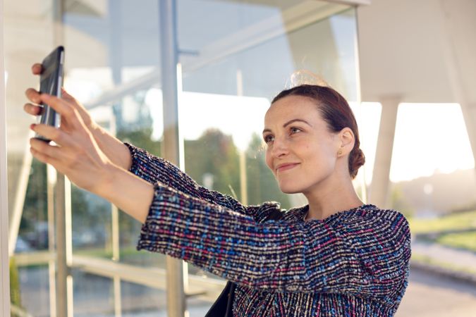 Smiling businesswoman taking selfie on street