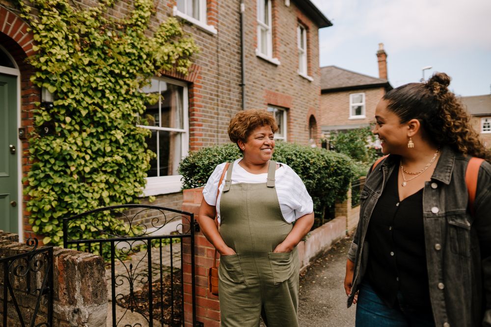 Two women talking while walking down a residential street