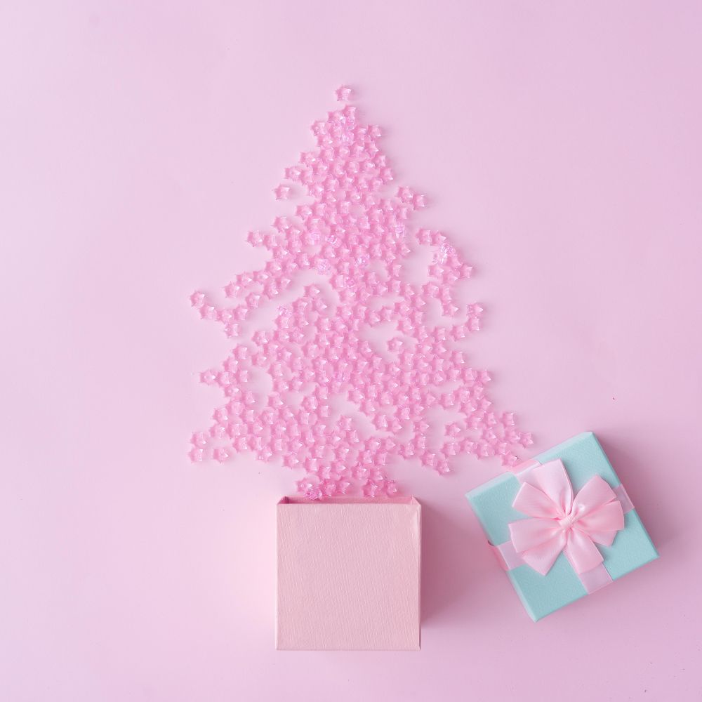 Christmas tree made of pink star decoration with blue gift box on pastel pink background