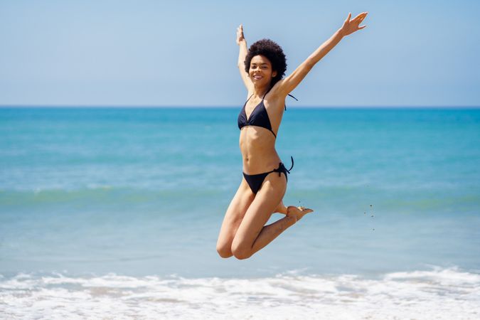 Woman jumping for joy in bikini at beach