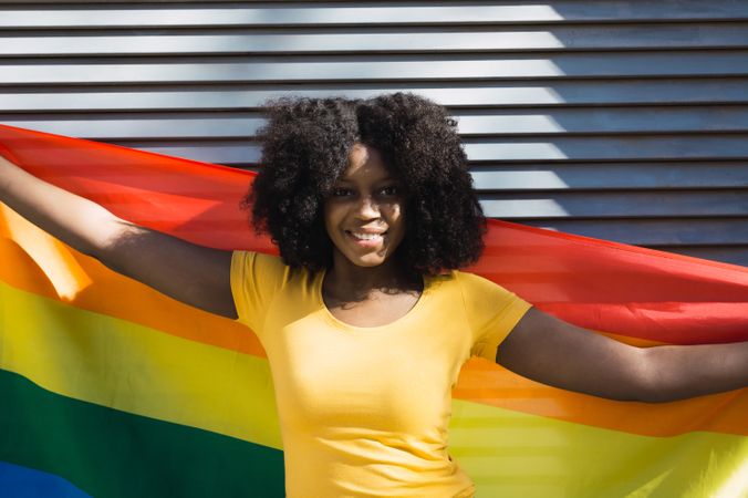 Black woman posing happily with the LGBT flag