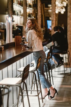 Stylish woman drinking wine in bar