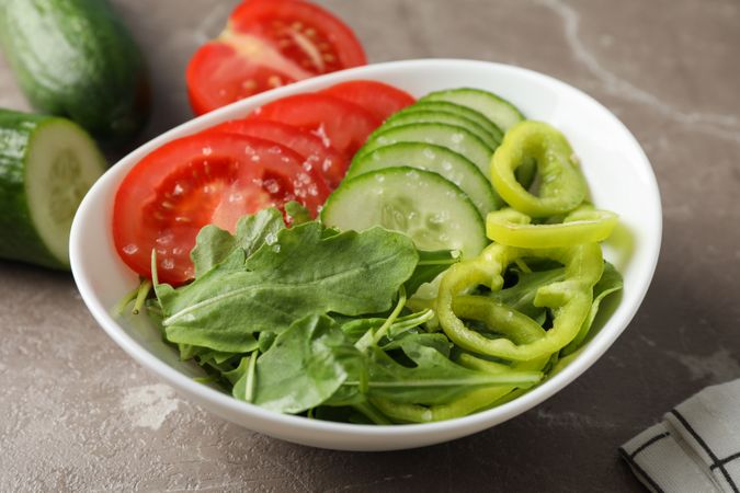 Plate with fresh vegetable slices on grey background, close up