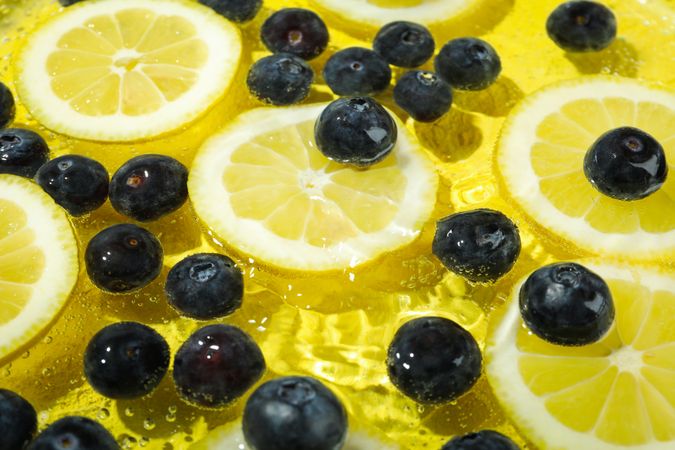 Top view of blueberries and lemons soaking in water with ripples