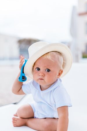 Blond baby with hat on the beach