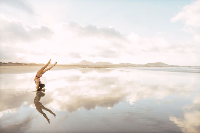 Woman doing handstand near sea