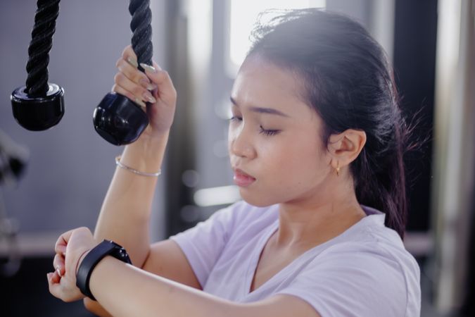 Focused Asian Woman Checking Progress on Smartwatch at the Gym