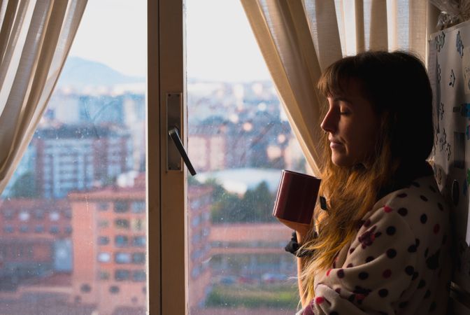 Woman enjoying hot beverage near fridge
