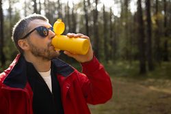 Man drinking from travel mug outdoors