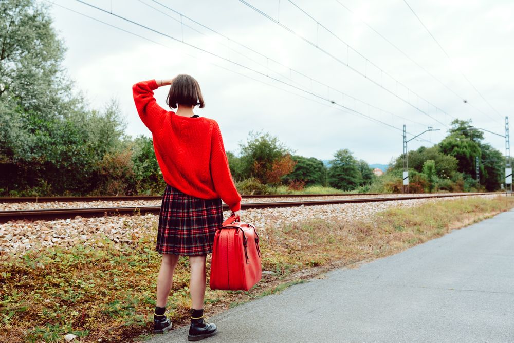 Woman looking at approaching modern train on railroad