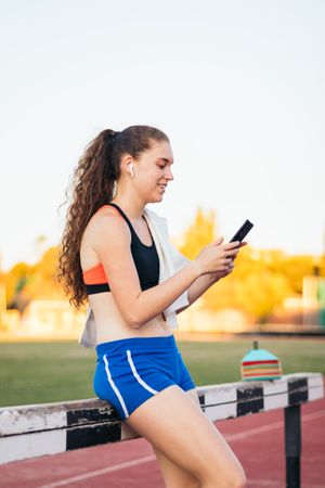 An athletic woman resting with her smartphone after running.