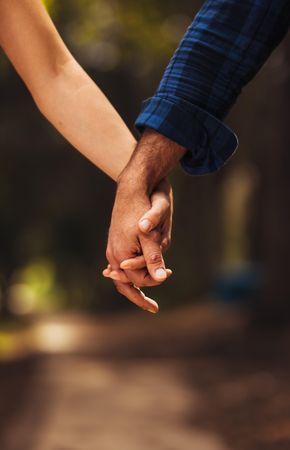 Close up of man and woman holding hands on a walk in the park