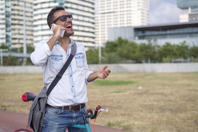 Laughing male on cell phone with city in background