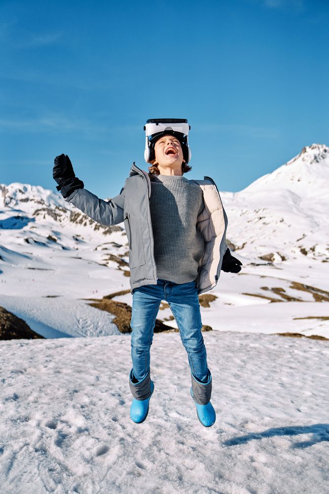 Cheerful boy jumping on snowy hill in VR