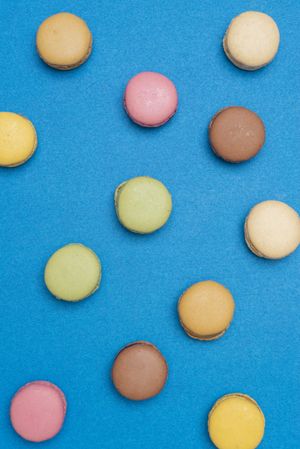 Top view of French pastel macaroons scattered on a blue table