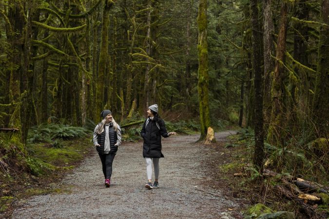Woman and young female talking among tall trees