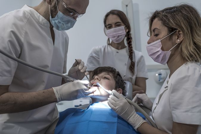 A portrait of dental team team working on young male patient with light