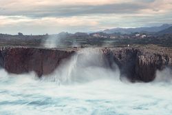 Powerful wave splashing at granite cliff