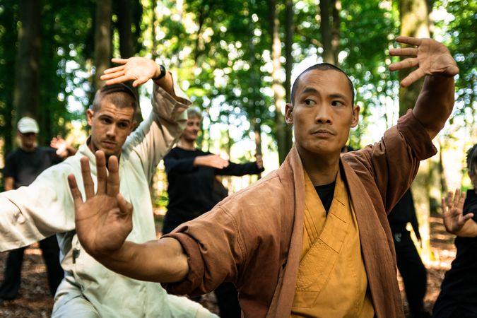 Asian martial arts instructor teaching group in forest