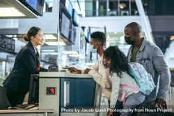 Tourists at check-in counter with airline attendant during pandemic bYR890