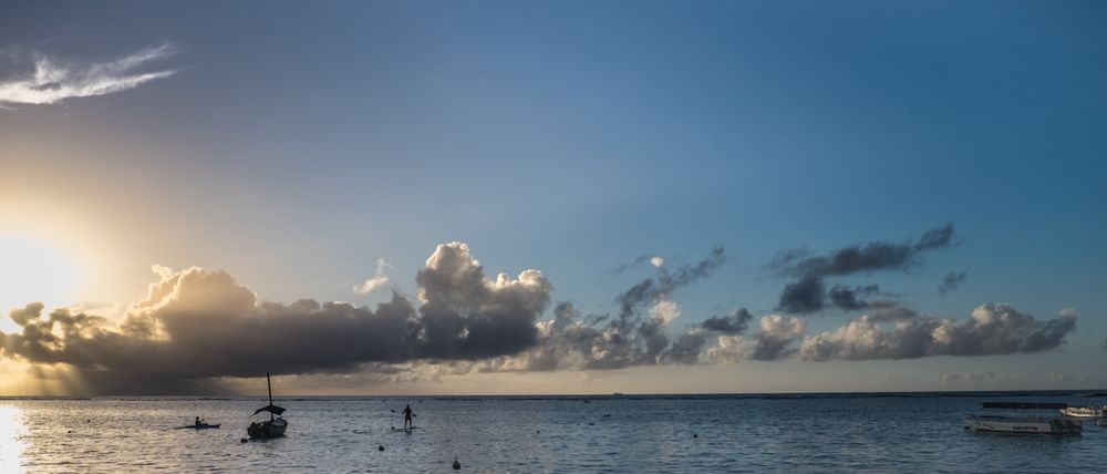 Person paddle boarding at dusk, wide