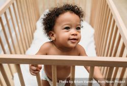 Cute baby boy standing up looking over his crib 5wGoZ5