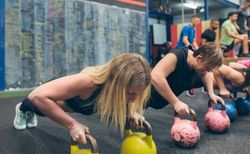 Sportswomen doing push-ups with kettlebells