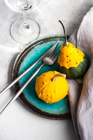 Two squashes on teal plate with cutlery
