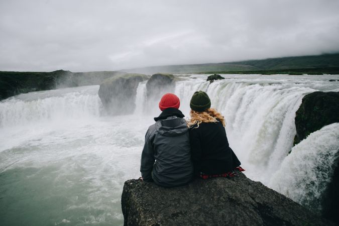 Man and woman sitting looking at waterfall