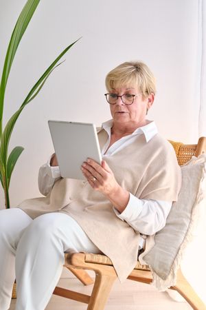 Older woman browsing internet on tablet in house