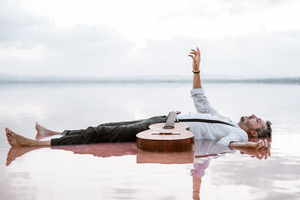 Man resting in water with guitar at seaside