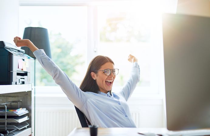 Woman with arms up in celebrating at her desk