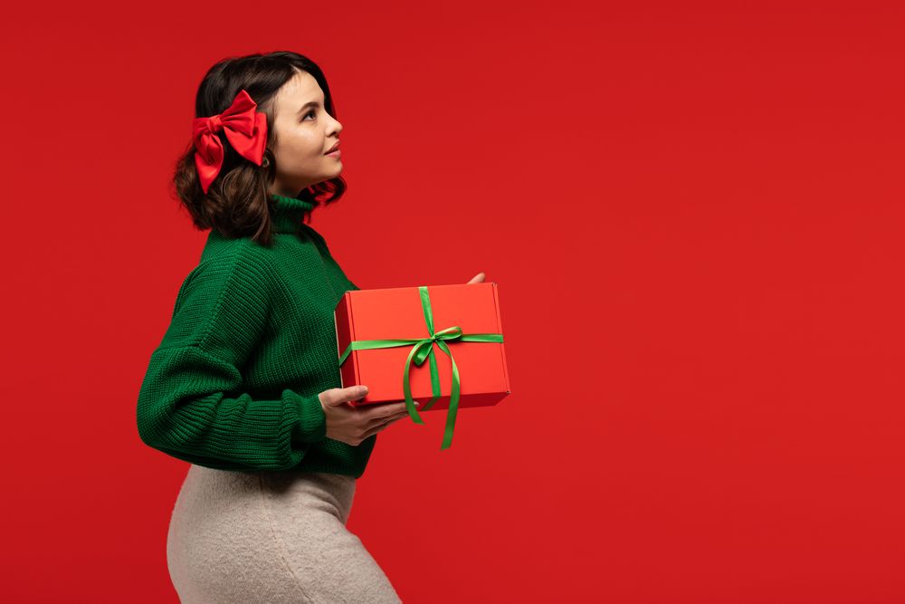 Woman with red bow in hair, holding gift box