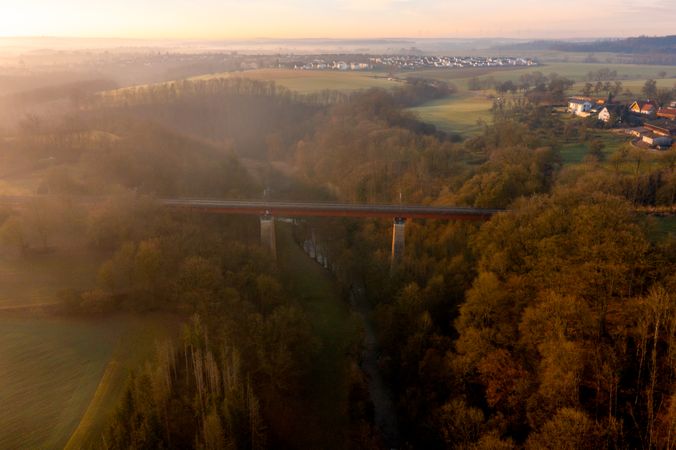 Drone aerial view of a railway bridge over a river into the forest