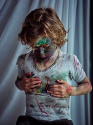 Dirty boy wiping paint on t shirt