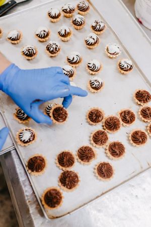 Anonymous baker decorating small cakes