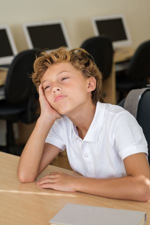 Weary pupil sitting at desk during lesson