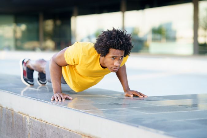 Man doing planks on cement wall outside