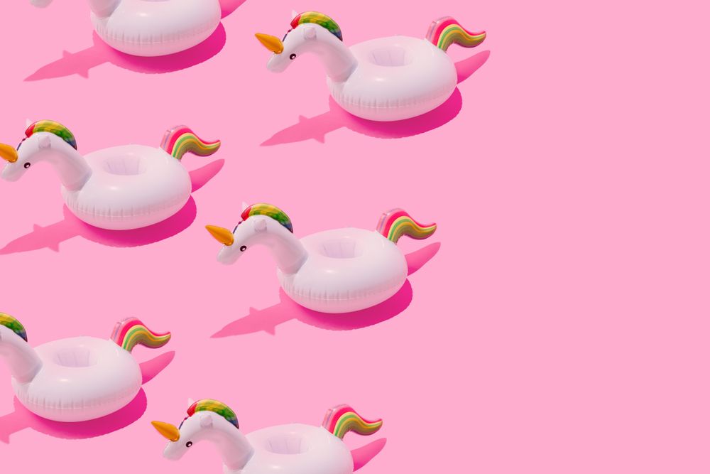 Inflatable unicorn pool toy on pastel pink background