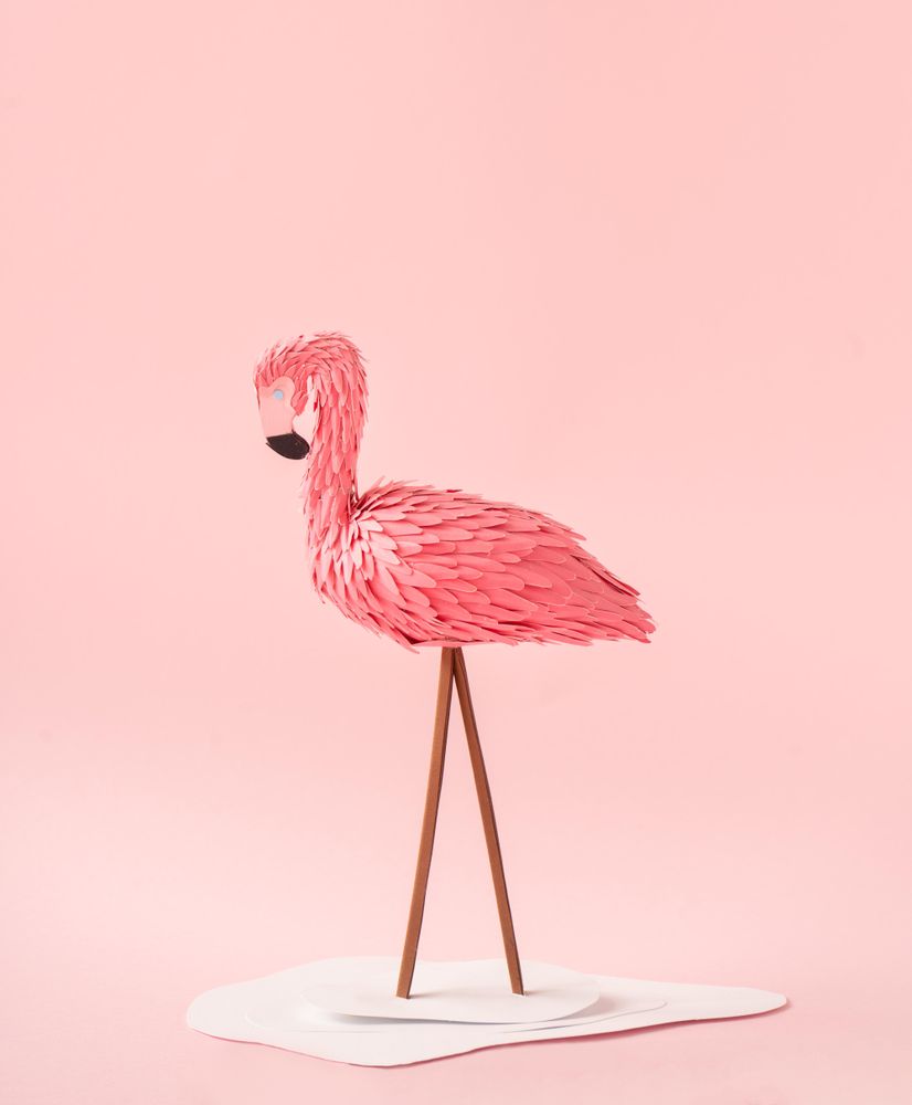 Flamingo made of paper on pink background