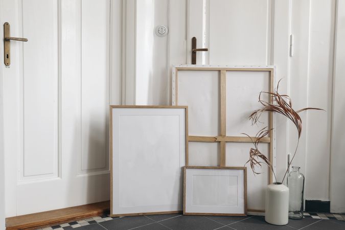 Boho wooden picture frames set and blank canvas mockups on grey tiles floor