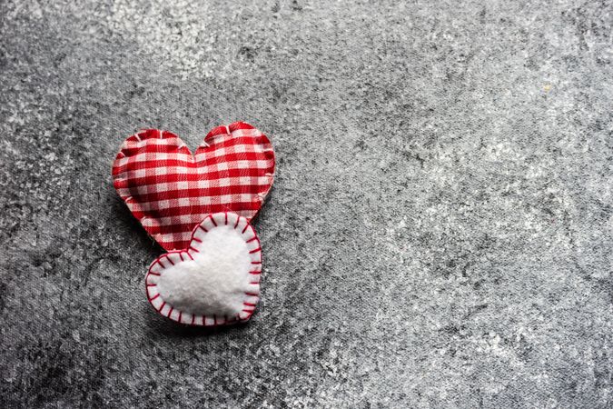 Valentine's day concept with two red felt hearts on grey counter