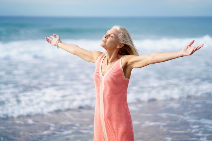 Mature woman with arms outstretched on the coast