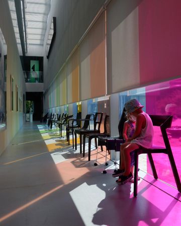 Two children sitting on chairs in a hallway