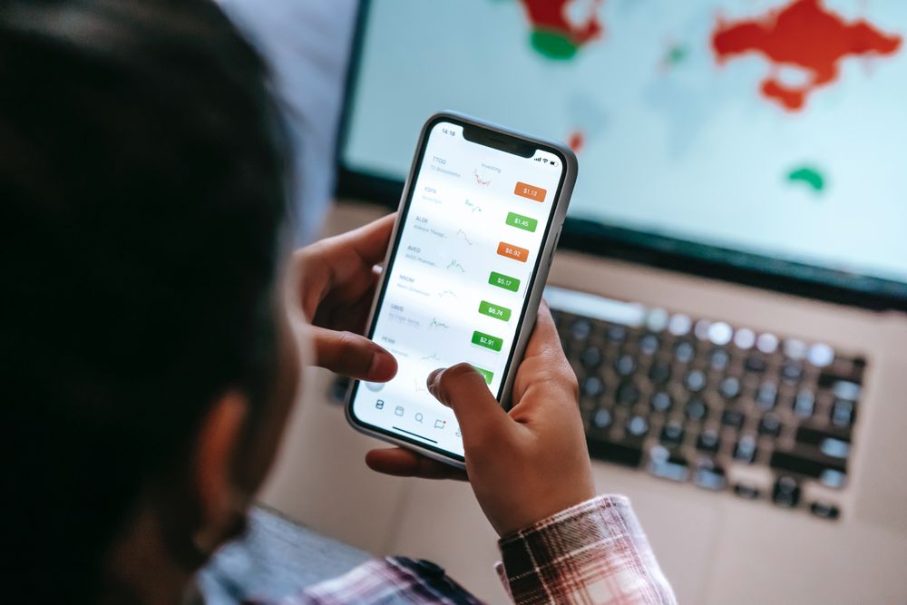 Back view of person checking stock market on their smartphone