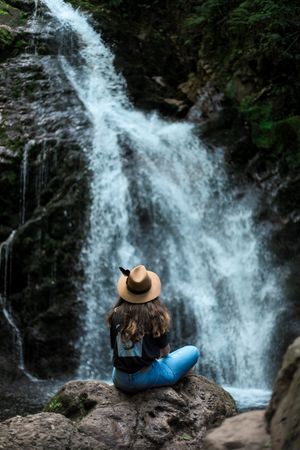 Smiling woman sitting near waterfall