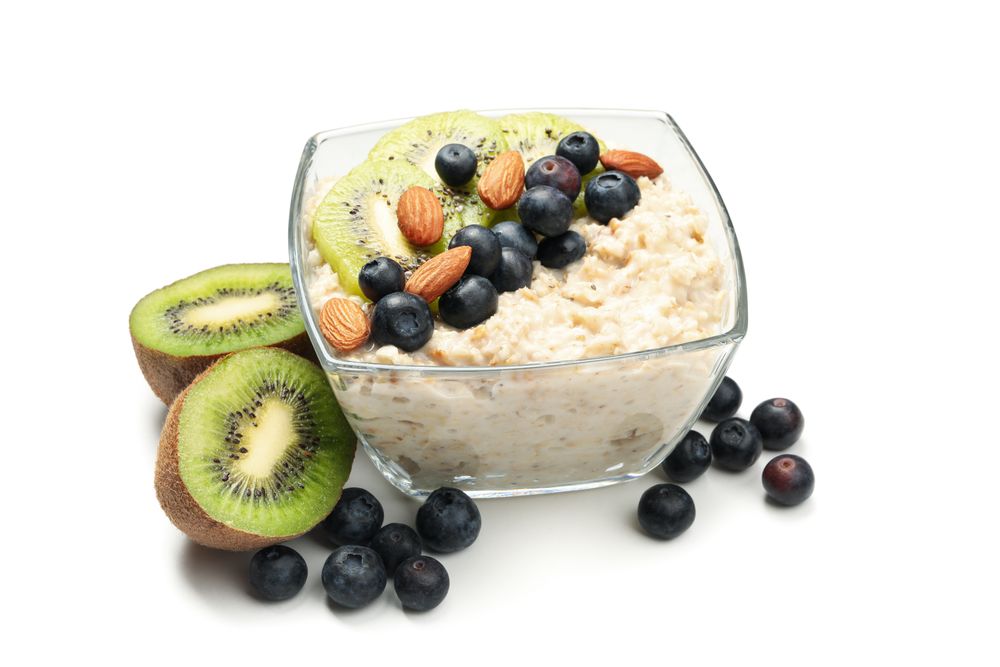 Bowl with oatmeal porridge and fruits isolated on plain background