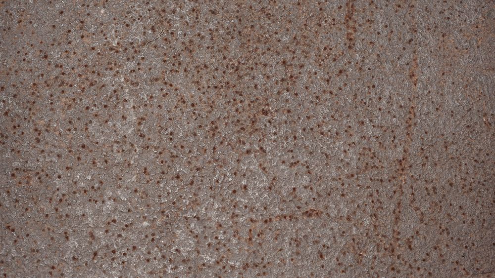 Rusted steel surface with fine granular corrosion and aged metallic texture