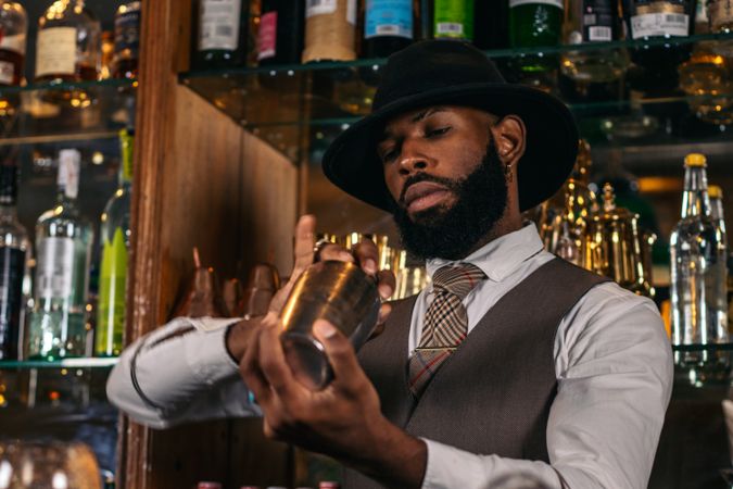stylish Black bartender preparing a cocktail in a shaker in a traditional cocktail bar