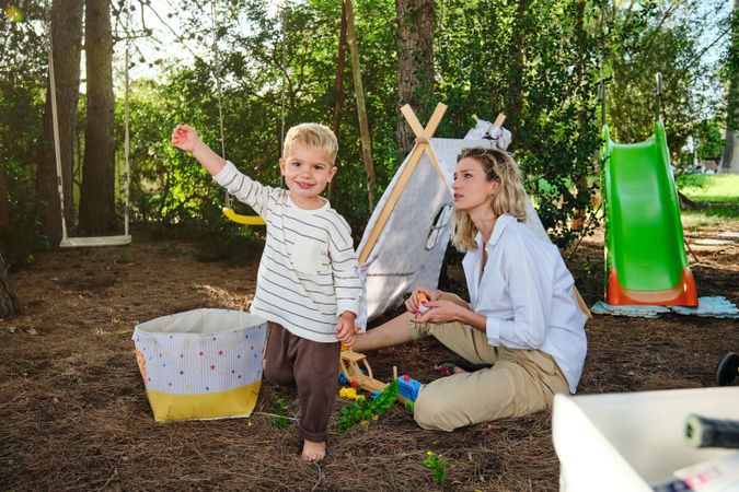 Happy boy with mother playing near tent in park